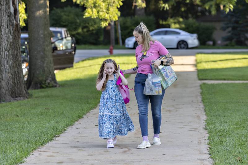 Stormy Baker, 6, fixes her hair as she walks to school with mom Emma Voss on Wednesday, Aug. 13, 2025, at Dixon’s Washington School.