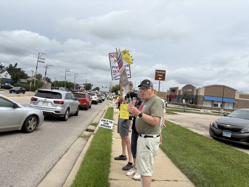 Protesters hold signs during a protest along Route 31 in McHenry July 26, 2025.