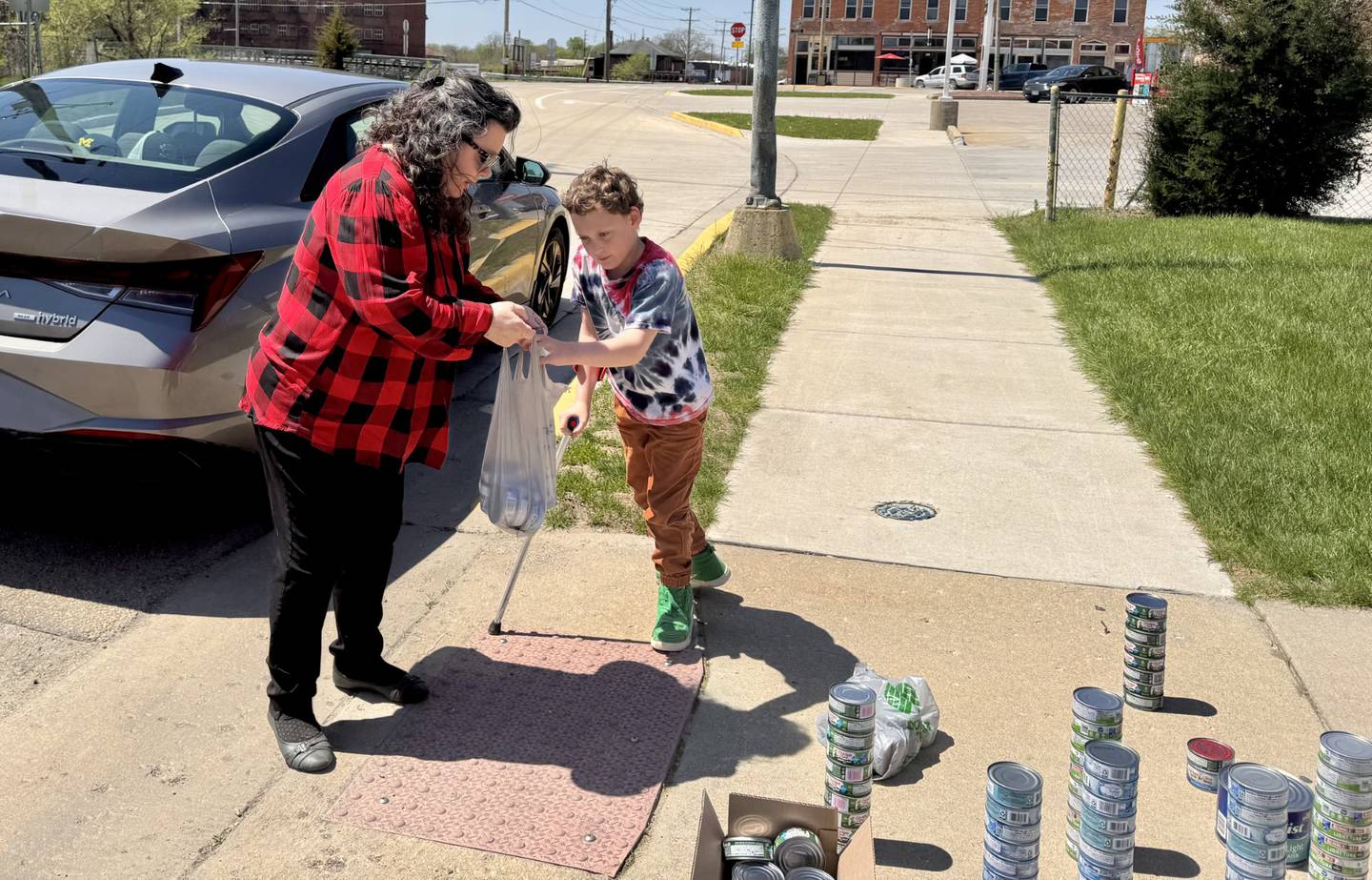 Tami Perryman, Pastor of Community of Christ Church, drops off cans of tuna to Maximilian Claahsen on Sunday, April 27, 2025.