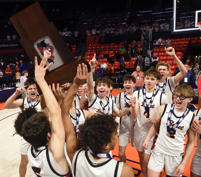 Benet Academy players celebrate with their state championship trophy at the conclusion of the IHSA Class 4A boys basketball state championship game against Warren at State Farm Center on Saturday, March 15, 2025 in Champaign.