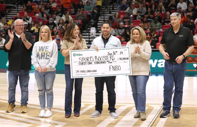 DeKalb and Sycamore boosters and staff along with members of FNBO pass a check Friday, Jan. 26, 2024, for $41 thousand dollars that was collected for this years event during the FNBO Challenge in the Convocation Center at Northern Illinois University.