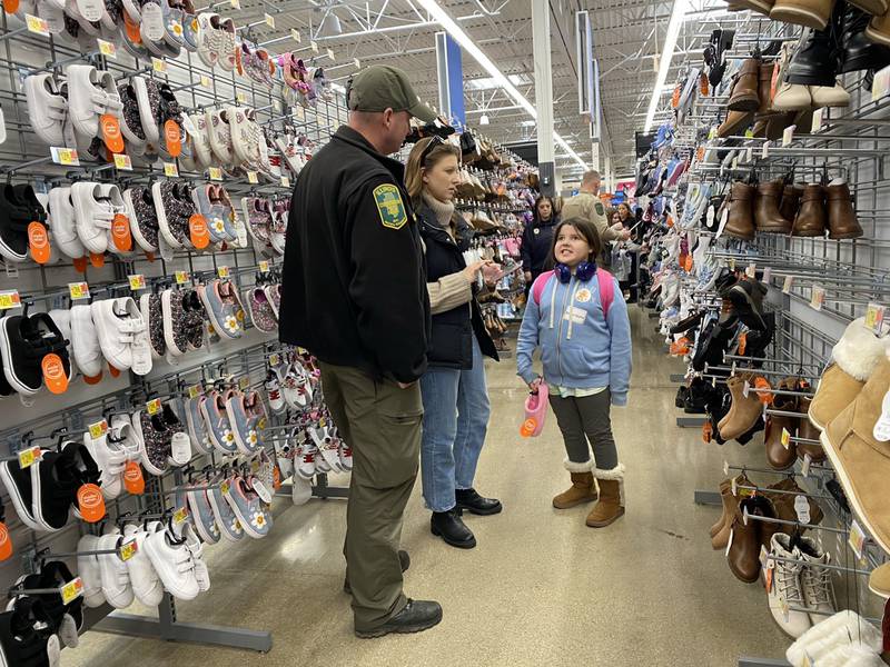 Dave Wolgast, with the Conservation Police and Grundy County Heroes and Helper volunteer Halee Barry help Alana R. pick out a new pair of shoes.