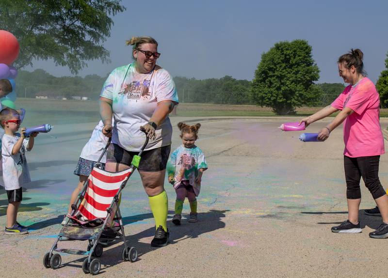 Volunteers celebrate those crossing the finish line with more color during CASA DeKalb County's annual 5K Color Run on Saturday, June 3, 2023. Shirts were provided for runners to wear as they ran the course.