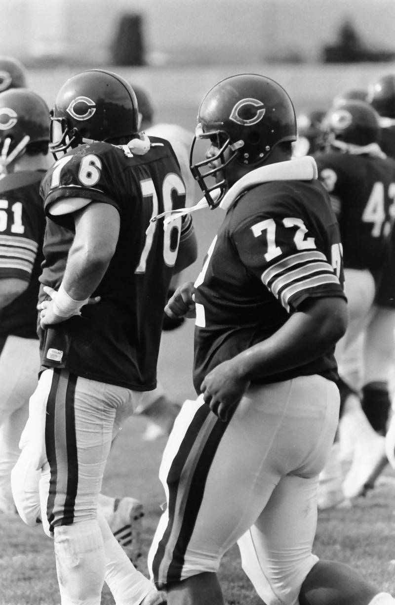 Chicago Bears defensive tackle William Perry "The Refrigerator" jogs up to the line of scrimmage with teammate Steve McMichael (left) during training camp on Wednesday, June 12, 1985 in Platteville Wis.