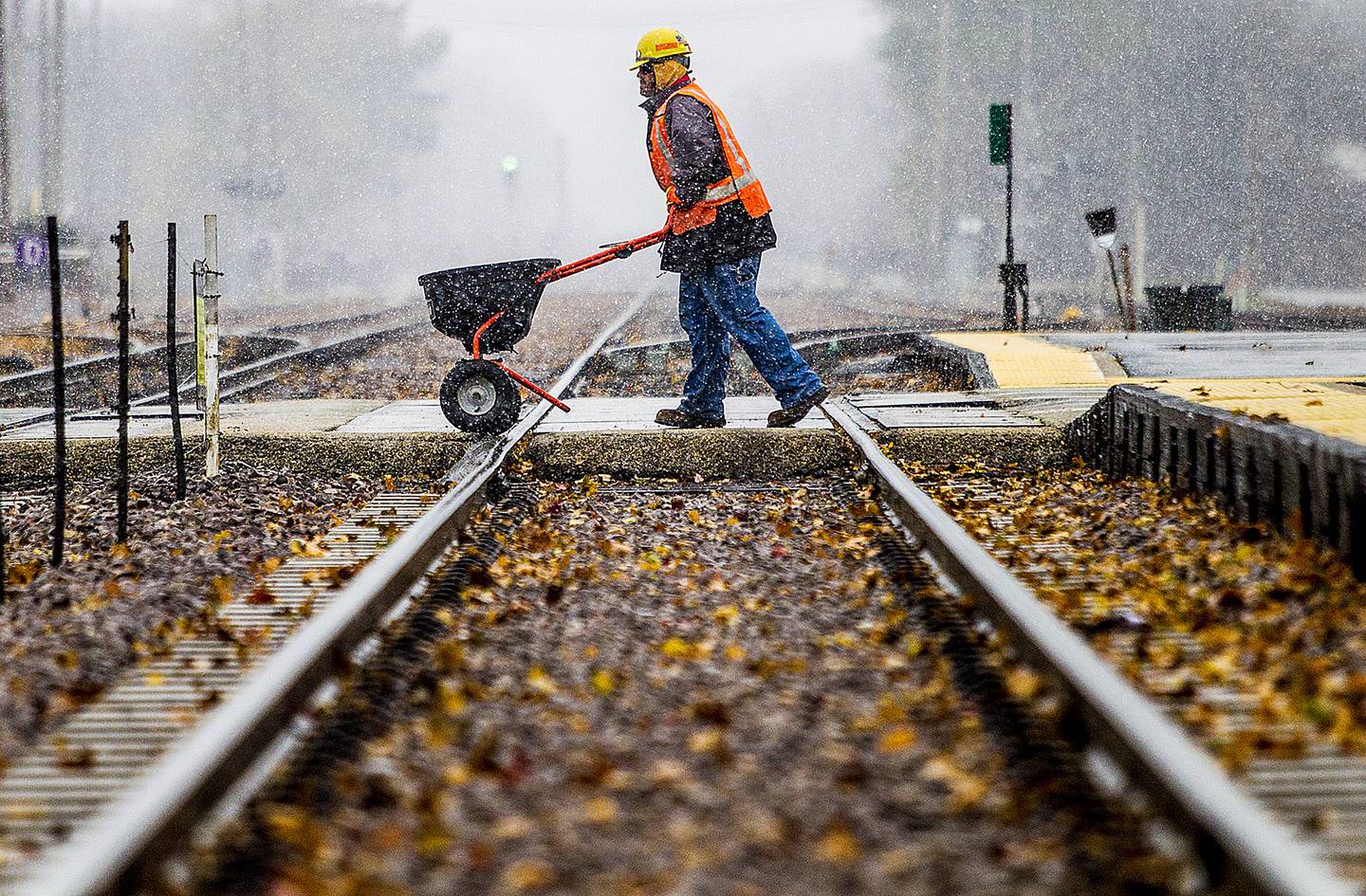Union Pacific track laborer Charlie Cox of Crystal Lake puts down salt along the walkways of the Crystal Lake Metra station on Monday, November 11, 2013.