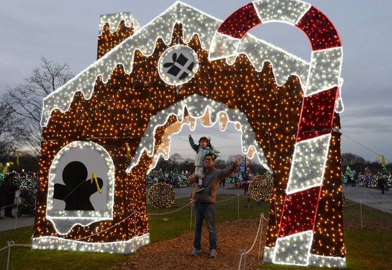 People including Ben Chung and his daughter Pearl of Chicago get their picture taken near the Gingerbread house during the Holiday event held at Brookfield Zoo Saturday Nov 26, 2022.