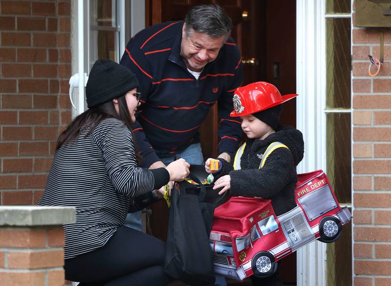 Kaitlynn Herbert and her son Henry, 3, trick-or-treat at the home of Ron Hodge on Halloween, Friday, Oct. 31, 2025, in DeKalb.