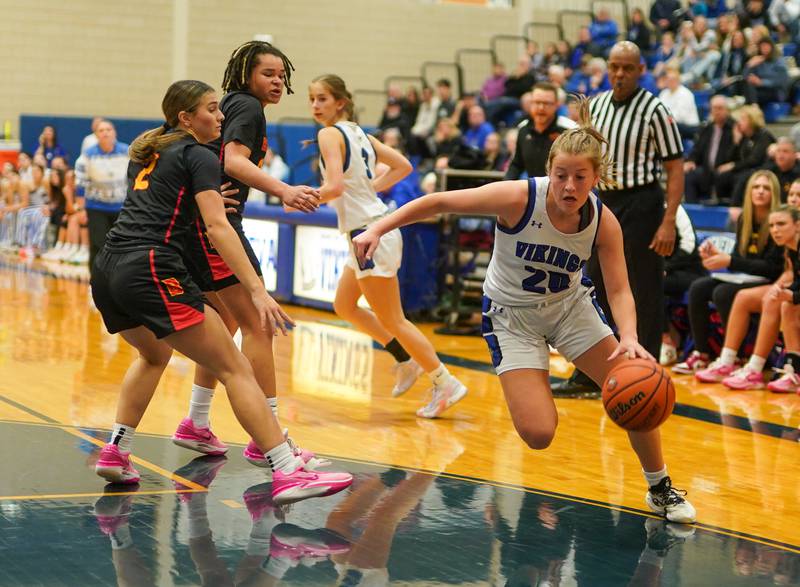 Geneva’s Caroline Madden (20) drives past Batavia's Brooke Carlson (2) and Addie Prewitt (23) during a basketball game at Geneva High School on Friday, Dec 15, 2023.