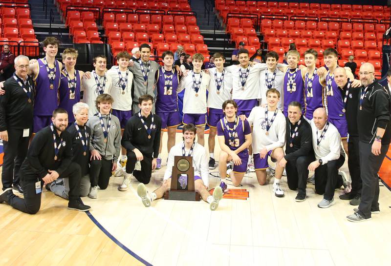 Members of the Downers Grove boys basketball team pose with their Class 4A fourth place trophy after loosing to New Trier the Class 4A state third place game on Friday, March 10, 2023 at the State Farm Center in Champaign.