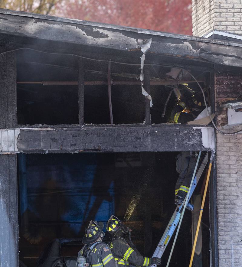 Using a chainsaw, firefighters cut into the ceiling of C&K Undercar Specialists to check for hot spots after a fire broke out at the Sterling mechanic shop.