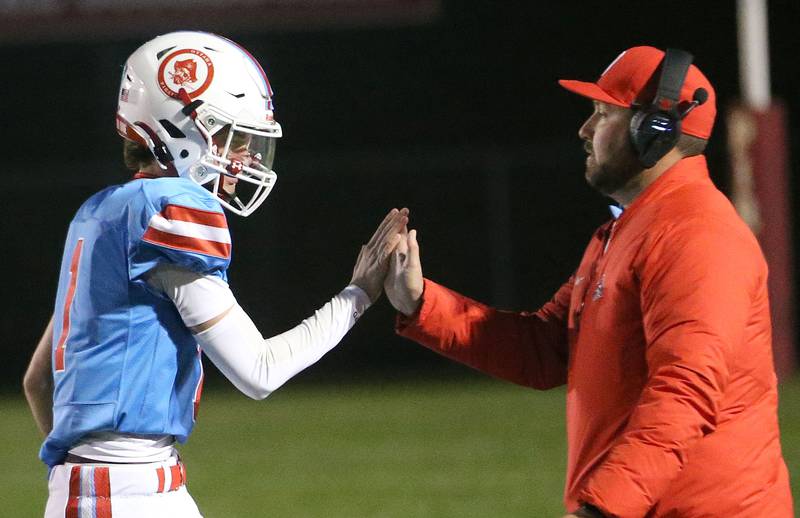 Ottawa quarterback Mark Munson hi-fives head coach Chad Gross after taking the opening snap against Granite City on Friday, Oct. 24, 2025 on King Field at Ottawa High School. Munson was injured with a concussion during the season and took the opening snap. k