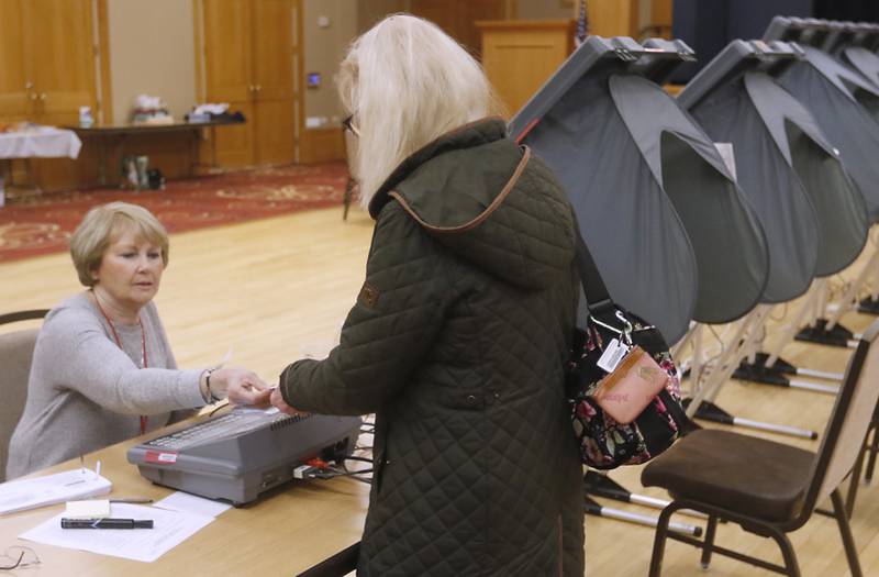 Election judge Sharon Lynch hands Amy Sanecki of Huntley her ballot information as she prepares to cast her votes Tuesday, April 4, 2023, in the 2023 consolidated election at Del Webb Sun City’s Prairie Lodge in Huntley.