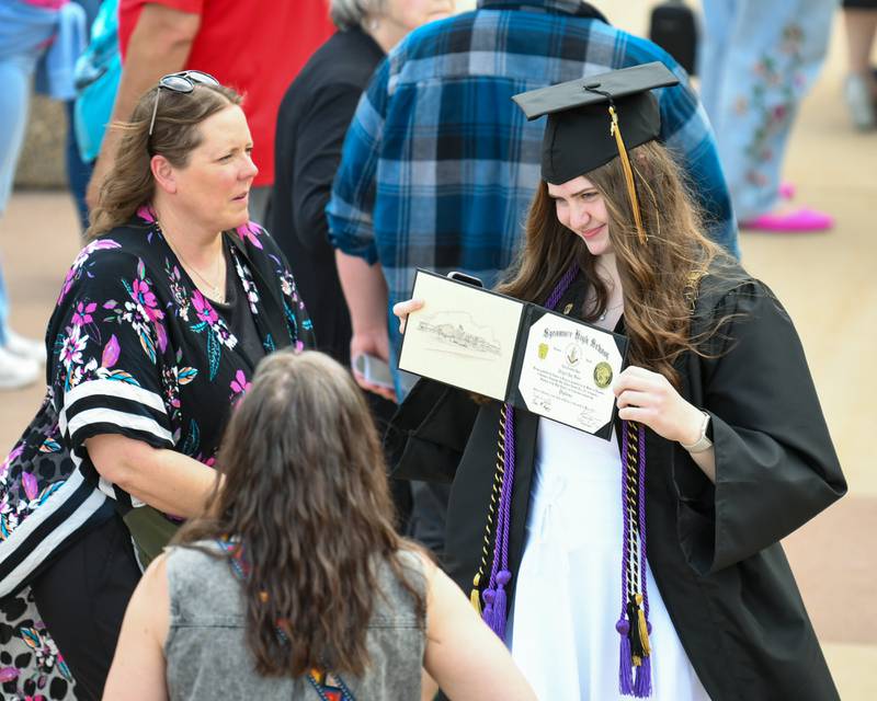 Sycamore High School senior Abigail Oster shows off her diploma on Sunday, May 25, 2025, during the Class of 2025 Commencement ceremony at the high school.