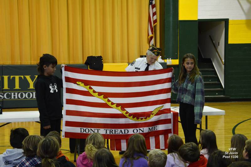 Students  (from left) Carter Shain and Lila Symons holding the First Navy Jack  alsothe first flag used by the United States Marine Corps. This flag is believed to have flown aboard the Continental Fleet's flagship Alfred. In January, 1776. Commodore Esek Hopkins raised this flag to signal his fleet to attack British ships.