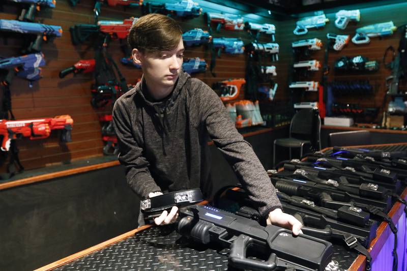 Associate Andrew Gordon sets out laser tag guns on the counter for customers at Twisted Limits Laser Tag on Tuesday, Dec. 14, 2021, in McHenry.  The business opened last December.