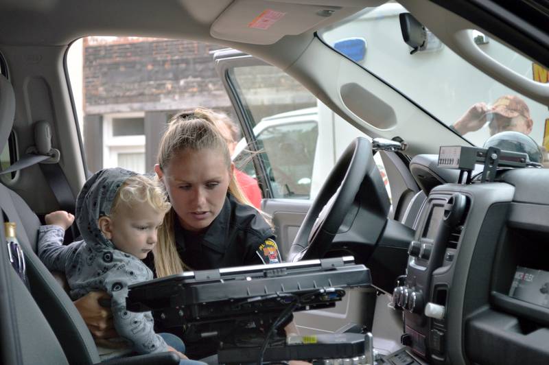 Mt. Morris police officer Cassie Rogers shows Logan LeFevre, 2, of Mt. Morris, her patrol car on Tuesday, Aug. 6, 2024, during the village's first National Night Out.