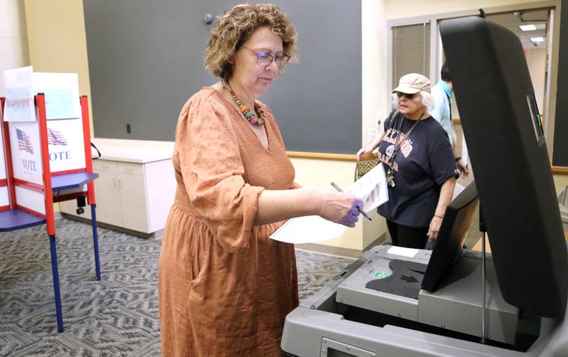 Peggy Carey, from DeKalb, inserts her ballot into the collection machine during the early voting period Thursday, May 19, 2022, at the polling place at the DeKalb County Legislative Center in Sycamore. Early voting opened Thursday ahead of the June 28 primary election.