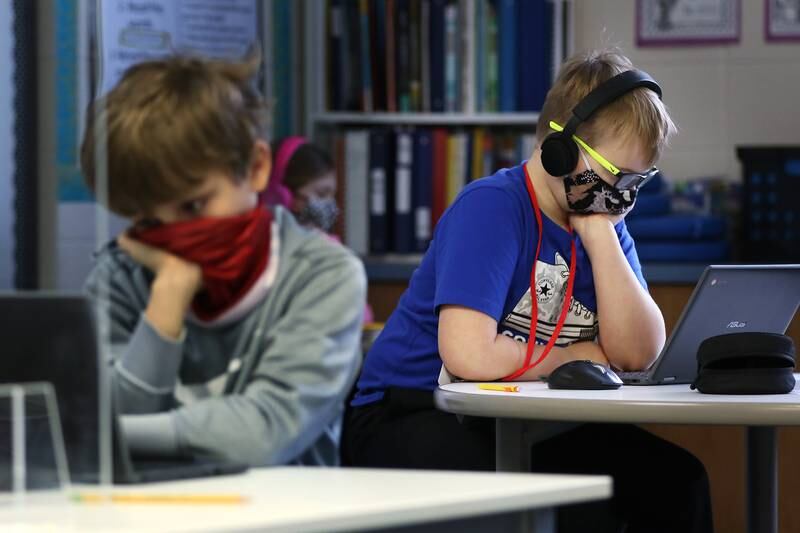 Ryan Rathjen, left, and Kane Freund, second grade students at Woods Creek Elementary School, work on a computer exercise inside their primary multiage classroom with teacher Carrie Thomas, which combines students in first and second grades, on Monday, Jan. 11, 2021 in Crystal Lake.  Students returned to school today to a hybrid learning model which incorporates a few hours of in-person learning.