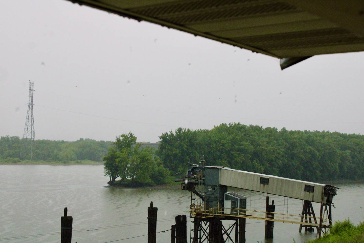 Rain droplets pour off the roof of a shelter at the Illinois River boat ramp in Hennepin during storms Saturday.
