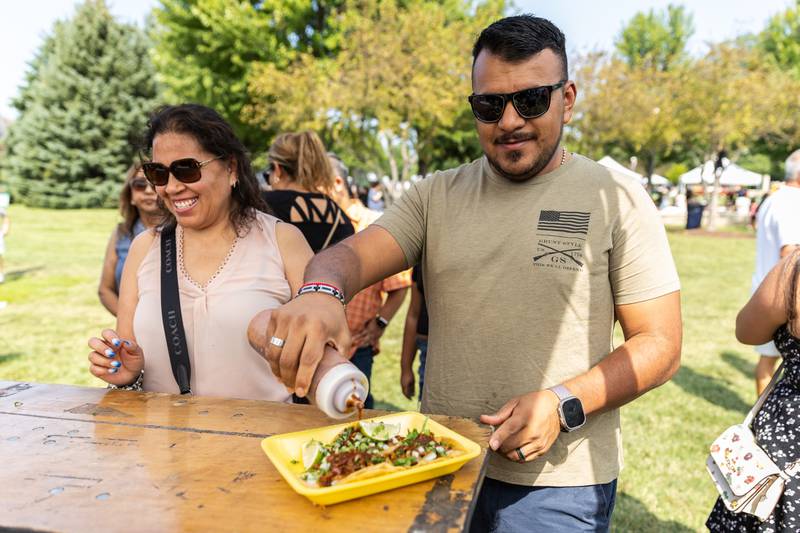 Norma and Ernesto Ledesma pick-up tacos from the El Aconaz Restaurant booth during Barro Fest at Settlers' Park in Plainfield on July 27, 2024.