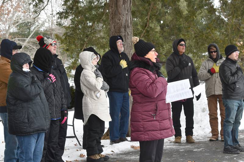 Laurie Carlin-Perry (right), a regent with the Rochelle Chapter of the Daughters of the American Revolution, takes part in the Pledge of Allegiance at the start of the Wreaths Across America program at the Daysville Cemetery on Saturday, Dec. 13, 2025.