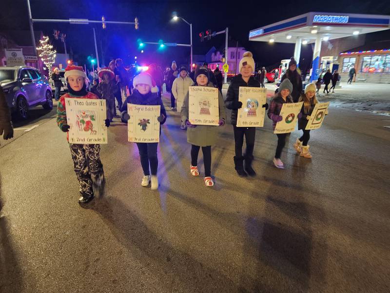 The winners of a holiday coloring contest walk in the 23rd annual Jingle Bell Parade during the Genoa Area Chamber of Commerce's annual Celebrate the Season holiday event on Dec. 6, 2024, in downtown Genoa.