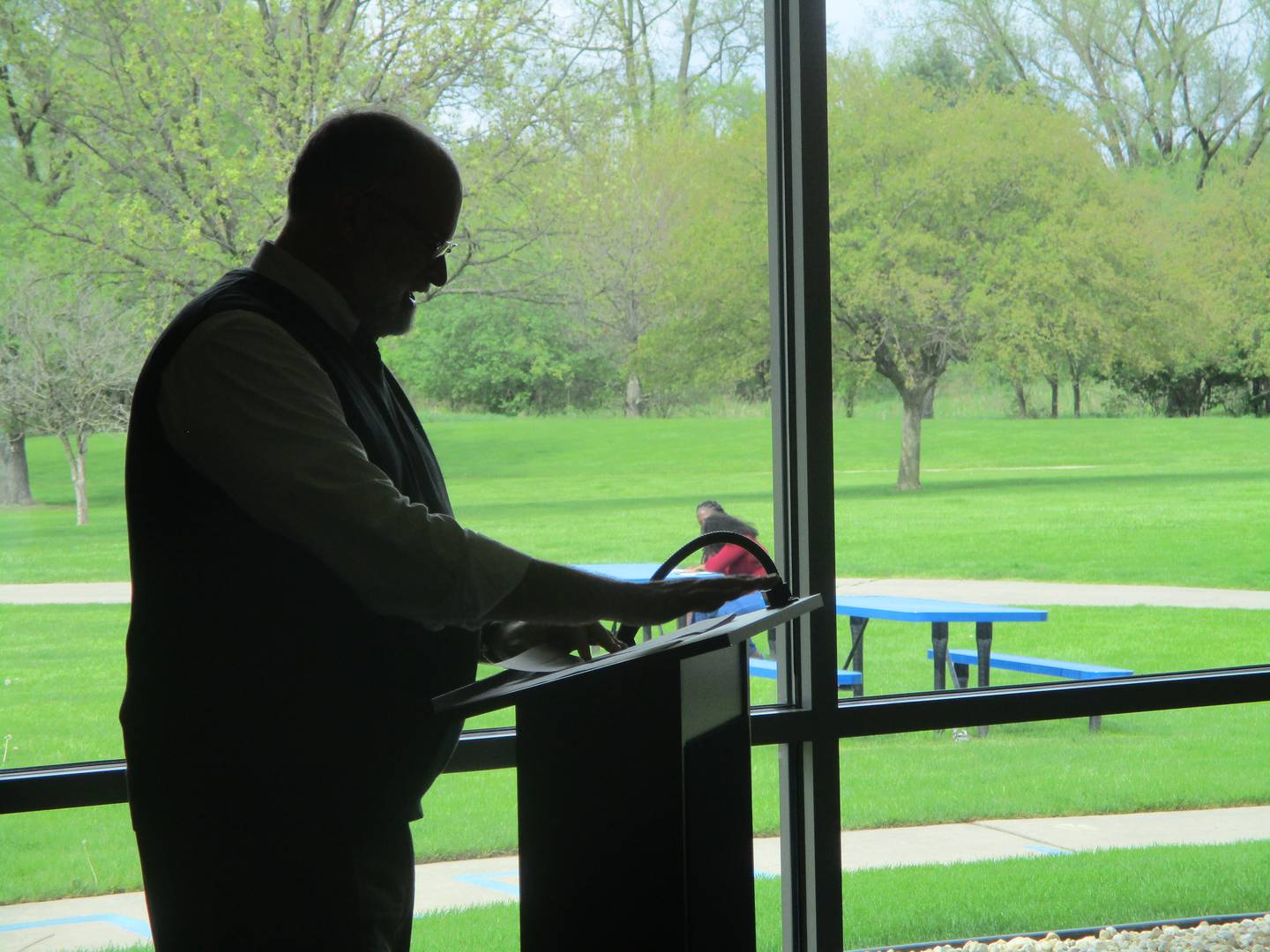 Joliet Public Library Deputy Director John Deiters at a ceremony on Friday is seen silhouetted in light coming through one of the large windows that look out upon a spacious lawn and the Rock Run Preserve outside of the library's Black Road Branch. April 24, 2025