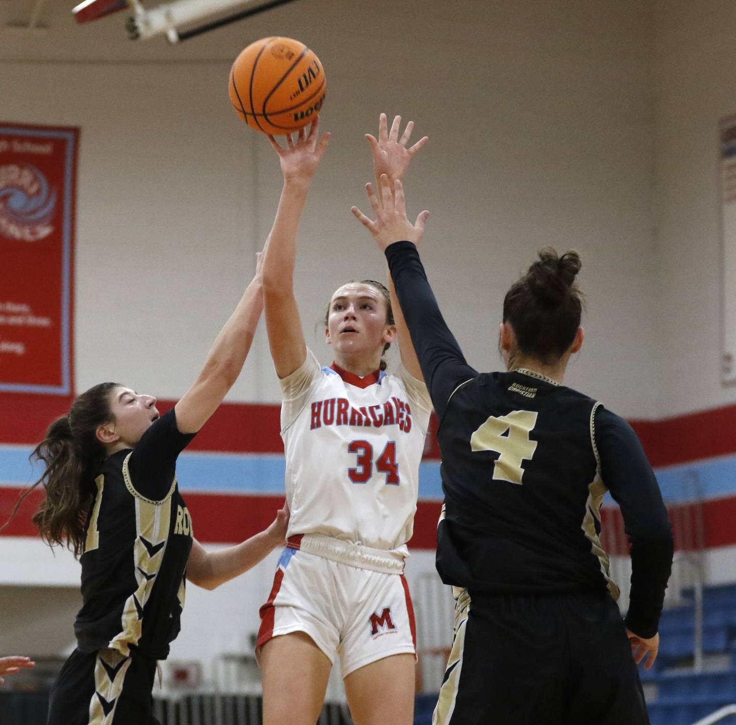 Marian Central's Juliette Huff shoots the ball between Rockford Christian's Lucy Gargani (left) and Teagan Lawver (right) during a nononference basketball game on Monday, Feb. 10, 2025, at Marian Central High School  in Woodstock.