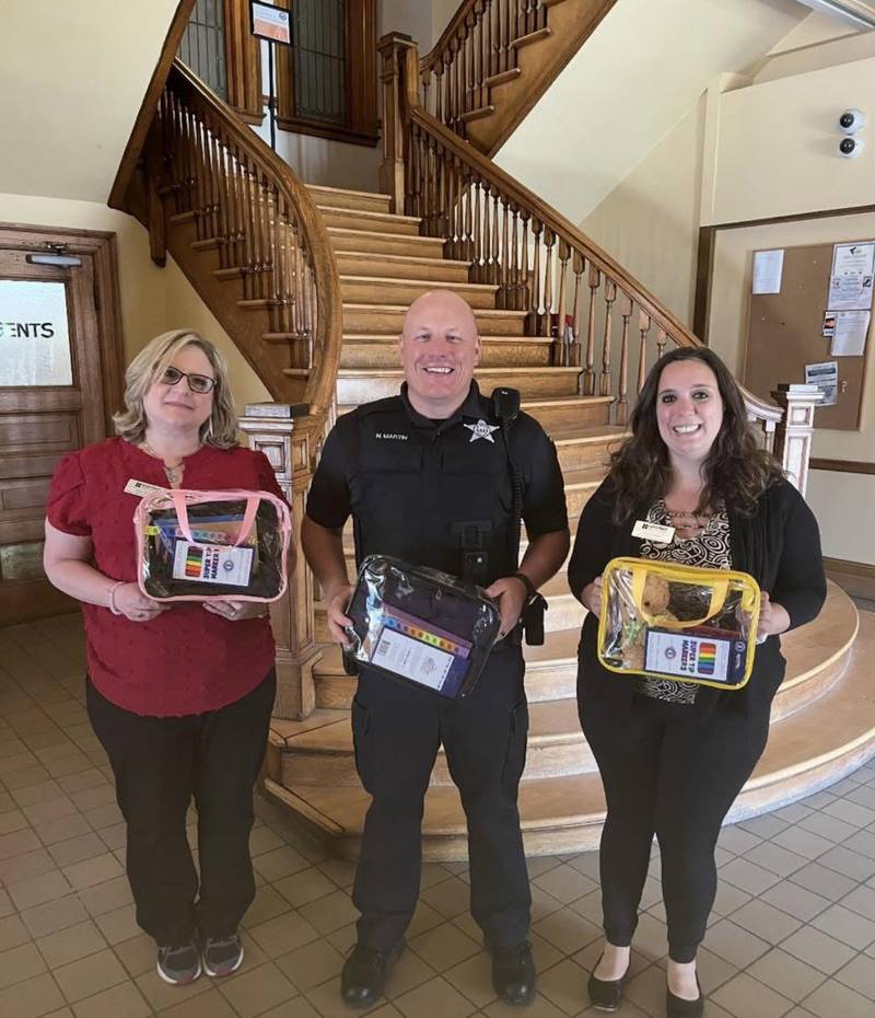 La Salle School Resource Officer Nick Martin stands beside Chestnut Health Systems representatives with comfort bags.