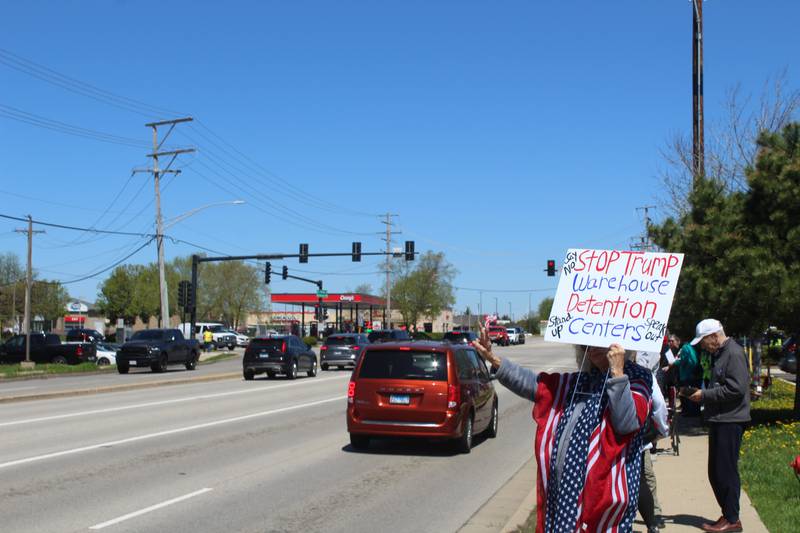 A woman holds up a sign protesting against detention centers to cars driving by on Route 31 on April 25, 2026, in McHenry.