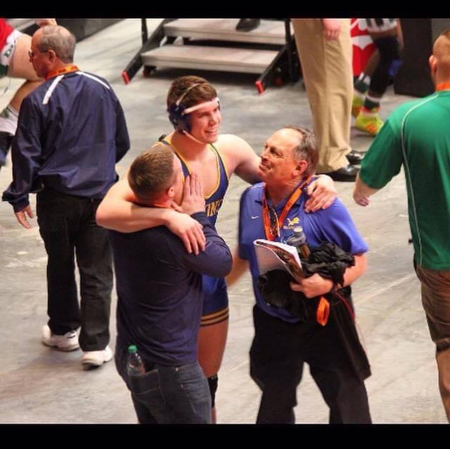 Lyons Township coach Mark King (purple shirt) celebrates with Frank Walsh and Coach Griff Powell after Walsh won his match to earn All-State honors.