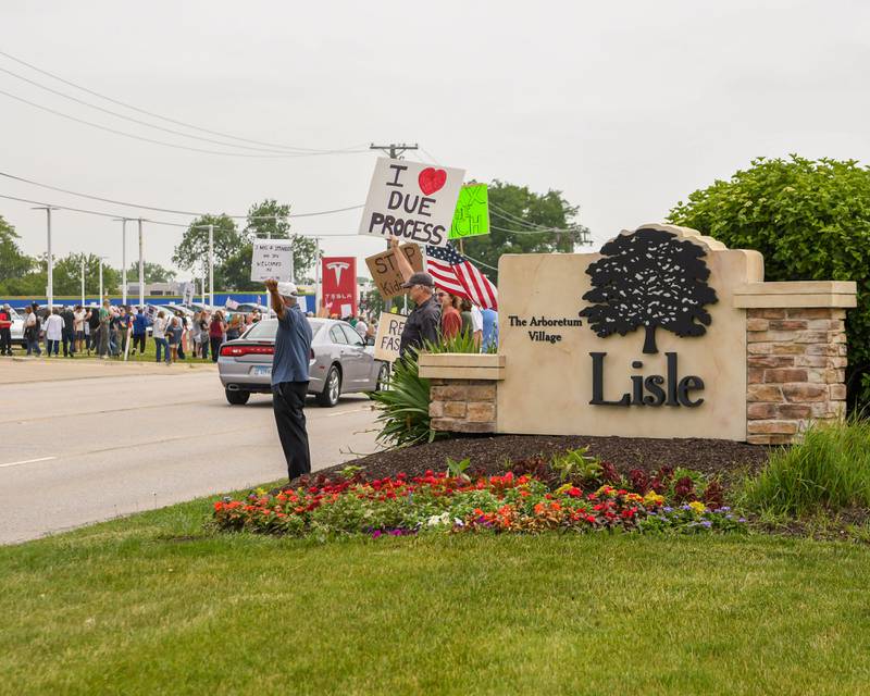 Community members hold signs during the No Kings rally in Lisle on Saturday June 14, 2025, held on Ogden Ave. near the Tesla dealership.