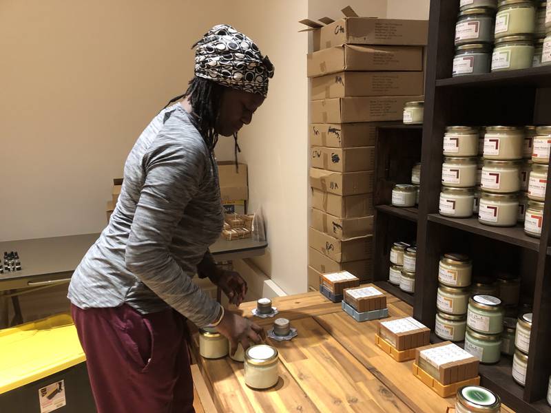 Julienne Samuels of Seleta Scents places merchandise on shelves ahead of the store's opening Wednesday.