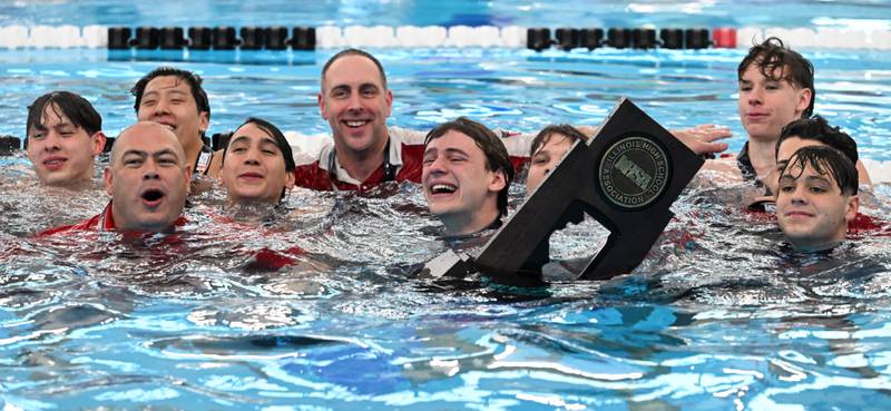 Hinsdale Central swimmers celebrate their state championship after diving into the water with the trophy during the boys state swimming and diving finals at FMC Natatorium on Saturday, Feb. 24, 2024 in Westmont.