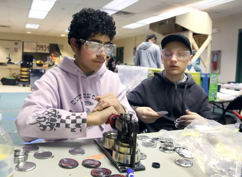 DeKalb High School Crowbotics Team members Jheyland Hernandez, (left) a freshman, and Elijah Lombardo, also a freshman, make team buttons to give to fans Tuesday, April 10, 2024, at Huntley Middle School in DeKalb. Crowbotics is DeKalb High School’s robotics team who has qualified to compete in the FIRST Robotics Competition World Championship held in Houston, Texas April 17-20.