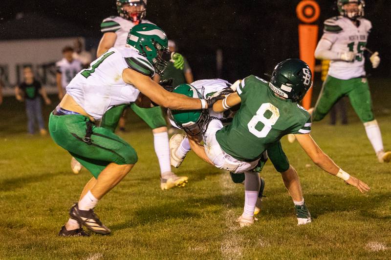 (from left) Brad Dahl (31) of North Boone helps teammate Collin Mckibben (9) bring down Gino Ferrari (8) of St. Bede while he hugs ball on Friday, Sept 12, 2025 at Captain Thomas J. Heitmann field in Peru.