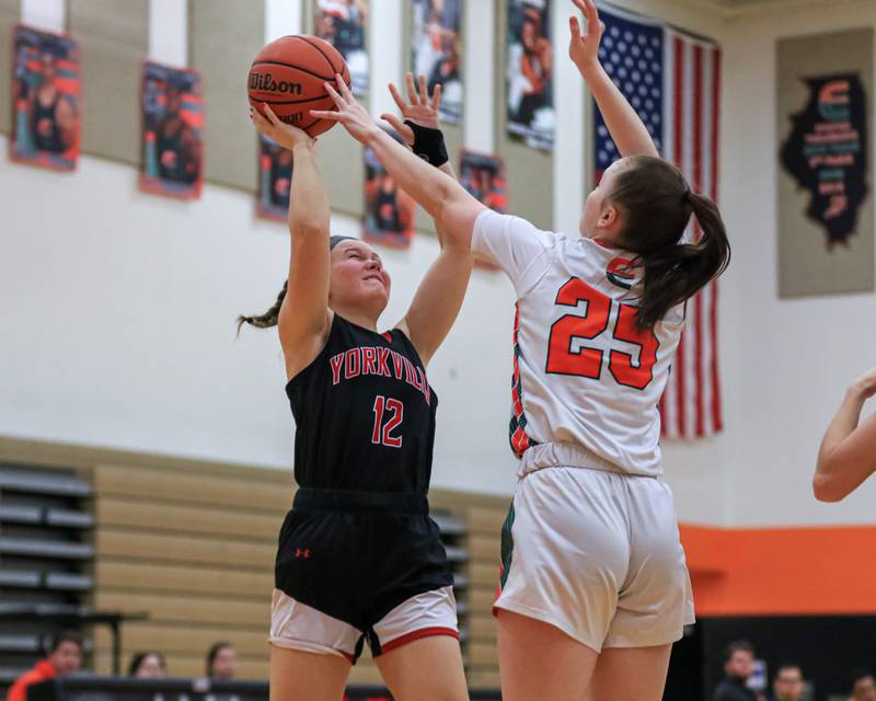 Plainfield East's Morgan Stephens (25) gets her hand on a jump shot attempt by Yorkville's Katlyn Schraeder (12) during varsity basketball game between Yorkville at Plainfield East.  Jan 3, 2023