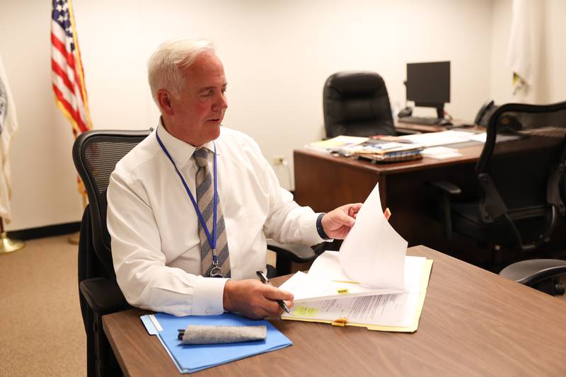 Mayor Terry D’Arcy’s desk sits in the background as he looks over papers at the conference table in his office, his preferred spot to work while at City Hall.