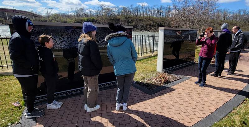 Linda Matter, group leader from the RiverGlen Christian Church, takes a photo of part of her group at the Middle East Conflicts Memorial Wall on Wednesday in Marseilles.
