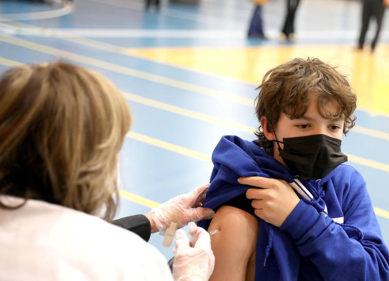 Brady Schlichter, 13, of La Grange is administered his COVID-19 booster shot by Laurie Larsen during a vaccination clinic at Lyons Township High School's North Campus in La Grange on Thursday, Jan. 20, 2022. The clinic was hosted in cooperation with Albertson's/Jewel-Osco.