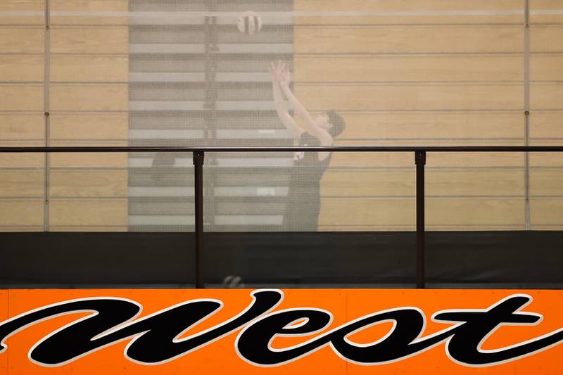A Lincoln-Way West varsity player warms up in the upper area of the gym as JV plays their match against Plainfield East on Wednesday, March 22nd. 2023 in New Lenox.