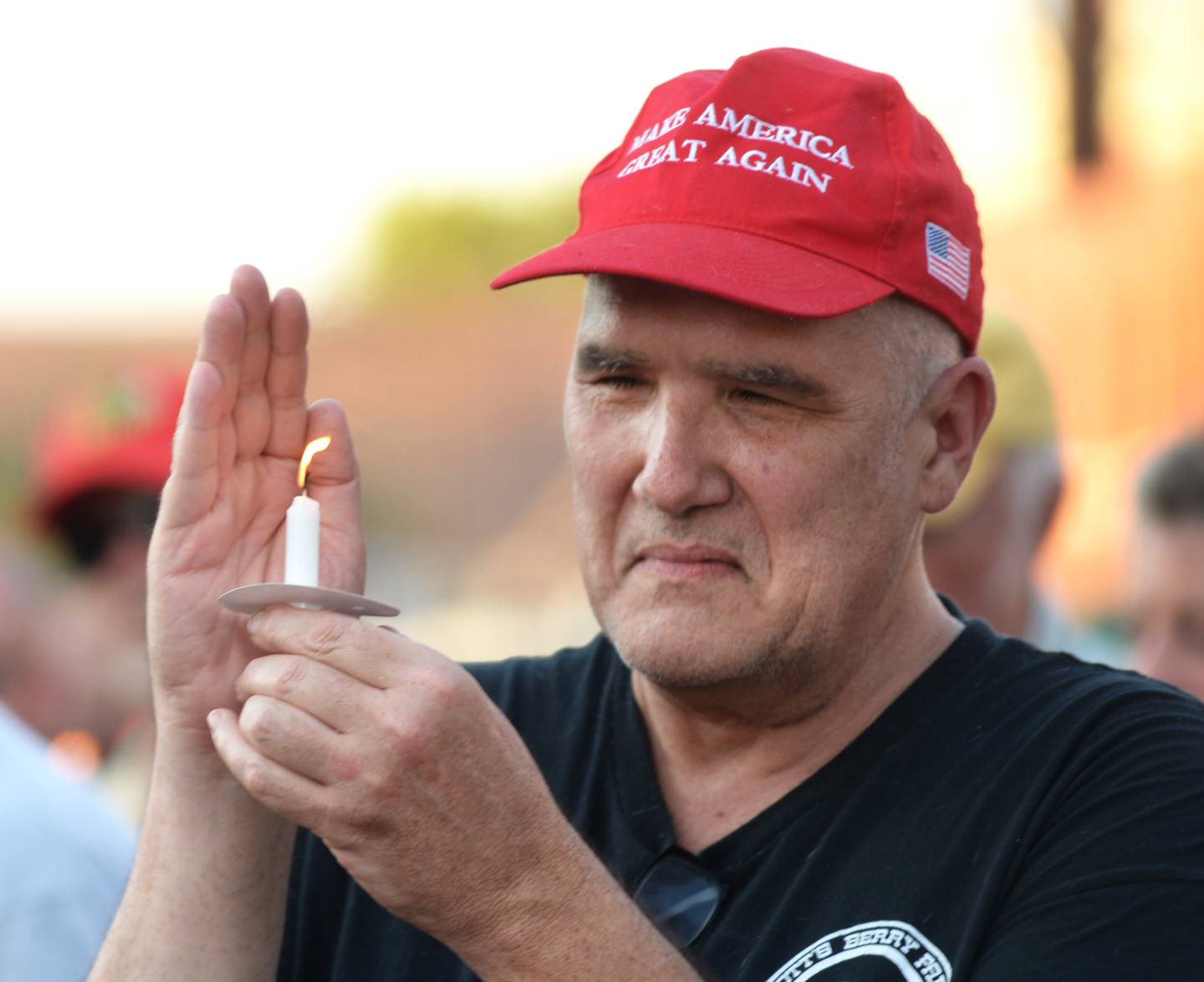 A man protects his candle from the wind during a candlelight vigil for Charlie Kirk held in downtown Oregon on Sunday, Sept. 14, 2025.