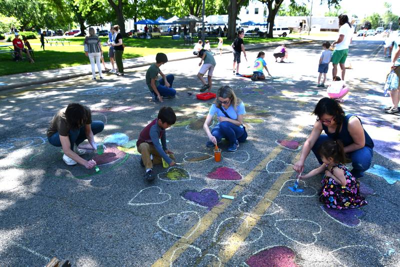 (Left to right) Ben Martinkus, Aleksander Martinkus, Amanda Pruss, MIssy Martinkus and Darah Martinkus draw on the sidewalk with chalk Saturday, May 27, 2023, during Sidewalk Chalkapalooza at Soldiers and Sailors Park in Princeton.