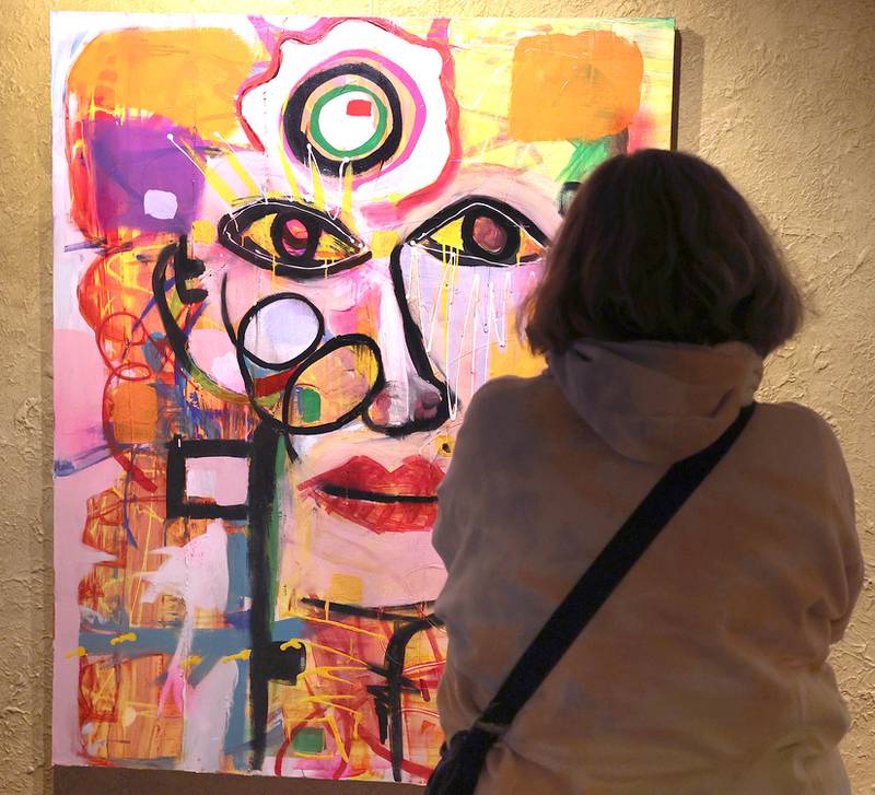 A visitor stops to look at a painting by Rudy Galindo during the Spring Art Exhibit opening reception Tuesday, March 22, 2022, at the Egyptian Theatre in DeKalb. The exhibit, featuring work from DeKalb County artists, runs until April 25.