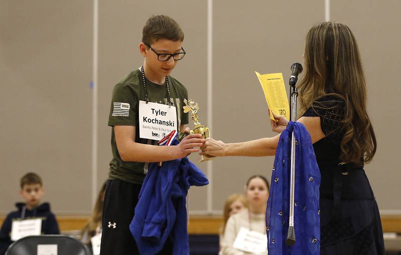 McHenry County Regional Superintendent Diana Hartmann hands Tyler Kochanski, a student at Saints Peter and Paul Catholic School, his trophy after he won the McHenry County Regional Office of Education’s 2025 Spelling Bee on Wednesday, March 19, 2025, at Bernotas Middle School in Crystal Lake.