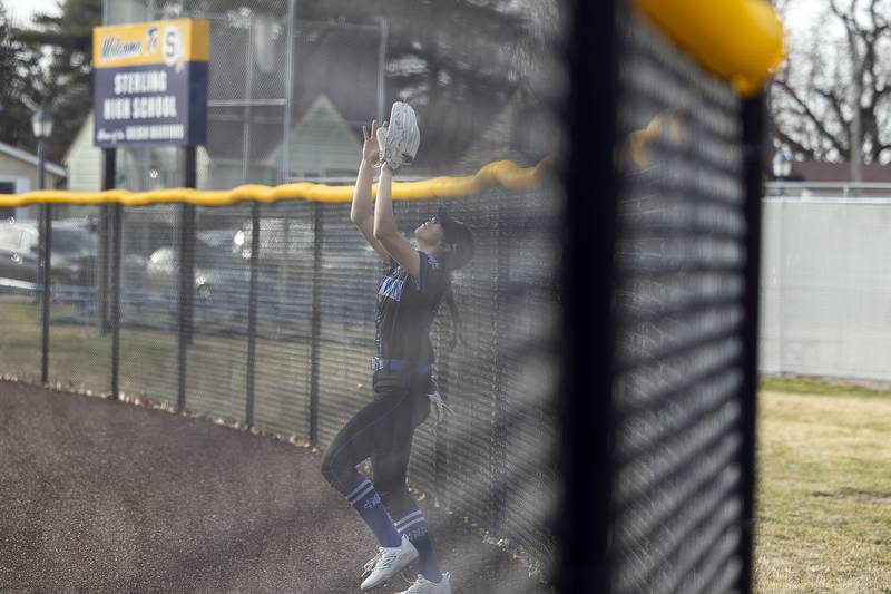 Newman’s Anna Propheter crashes into the centerfield fence after making a catch against Sterling Tuesday, March 18, 2025.