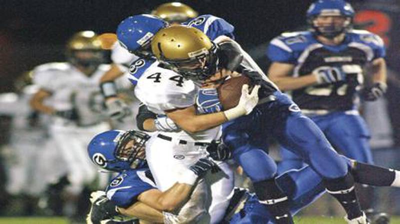 Sycamore running back Tom Hensley is brought down by Geneva defenders Trevor Hyslop (3) and Sean Grady (28) after a 39-yard reception during first quarter at Geneva Friday. The Spartans saw their record drop to 3-2 overall and 1-2 in the Western Sun. DON LANSU | Daily Chronicle