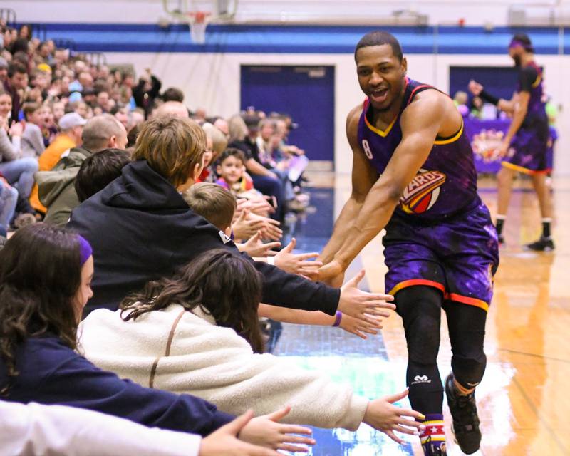 Harlem Wizard player Livewire gives high fives to the crowd as he gets introduced before the start of the game on Sunday Jan. 19, 2025, held at Downers Grove South High School.