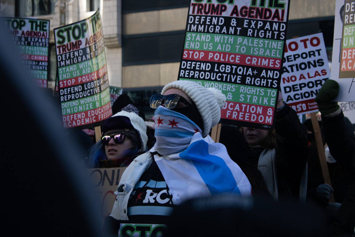 A protester masked with the City of Chicago flag stands among a crowd across the river from Trump Tower on Monday, Jan. 20, 2025. The protest occurred around the same time Donald Trump was inaugurated for his second non-consecutive term. (Photo by Ismael M. Belkoura for Medill Illinois News Bureau)
