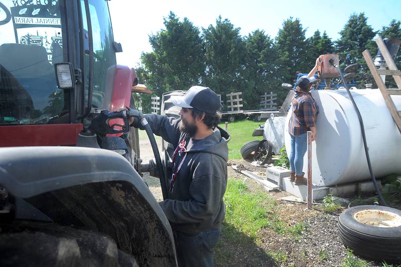 Farmer Bryon Kelly fills up his tractor with diesel fuel Friday, June 10, 2022, as Destiny West controls the pump on the fuel storage tank. The two were baling hay on their farm near Richmond. The rising cost of nitrate and fuels is raising the farmers' operational costs.